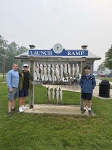 Happy anglers posing with a full limit of king salmon and steelhead at the Montague launch ramp after a successful Whitehall salmon fishing charter on Lake Michigan.