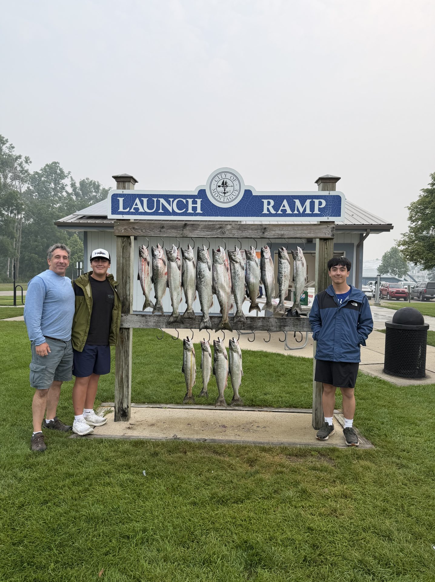 Happy anglers posing with a full limit of king salmon and steelhead at the Montague launch ramp after a successful Whitehall salmon fishing charter on Lake Michigan.